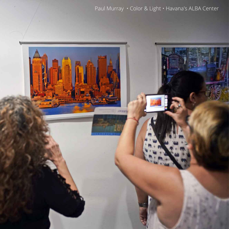 people viewing and taking pictures of an exhibit inside art gallery
